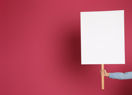 Woman holding blank sign on pink background, closeup. Space for designの写真素材