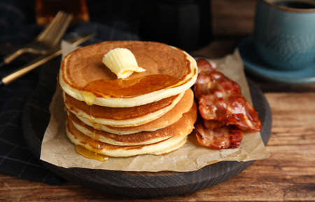 Delicious pancakes with maple syrup, butter and fried bacon on wooden tableの写真素材