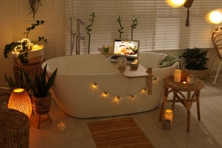 Stylish bathroom interior with green houseplants and string lights. Idea for designの写真素材