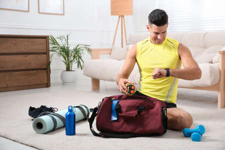 Man packing sports stuff for training into bag at homeの写真素材