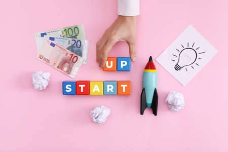 Woman forming words Start Up with colorful cubes on pink background, top viewの写真素材