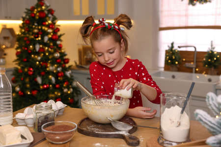 Cute little girl having fun while making dough for Christmas cookies in kitchenの写真素材