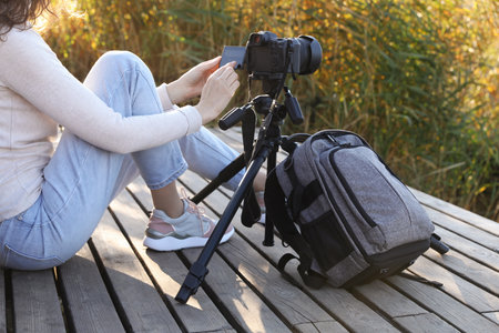 Photographer with tripod, modern camera and backpack on wooden pierの写真素材