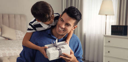 Man receiving gift for Father's Day from his son at homeの写真素材