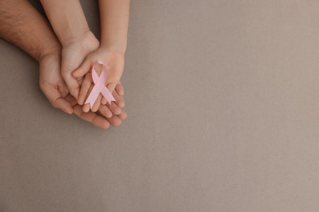 Family holding pink ribbon on gray background, top view with space for text. Breast cancer awarenessの写真素材
