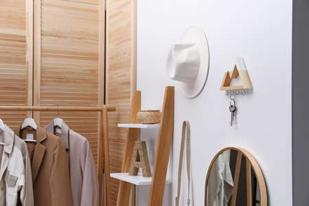 Modern hallway with stylish furniture, accessories and wooden hanger for keys on white wall....