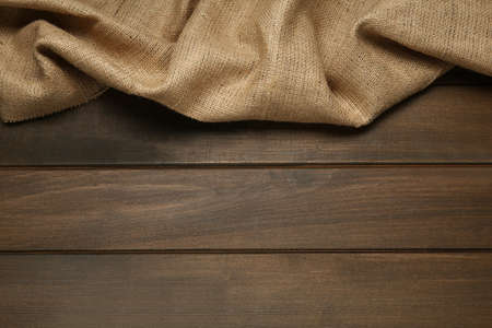 Natural burlap fabric on wooden table, top view. Space for text