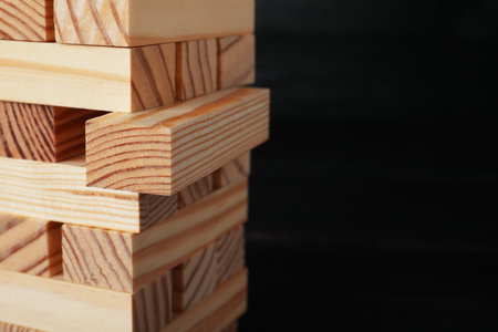 tower made of wooden blocks on black background, closeup. Space for textの写真素材