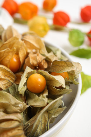 Ripe physalis fruits with dry husk on white table, closeupの写真素材