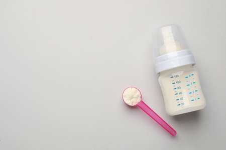 Feeding bottle with infant formula and powder on light background, flat lay. Space for textの写真素材