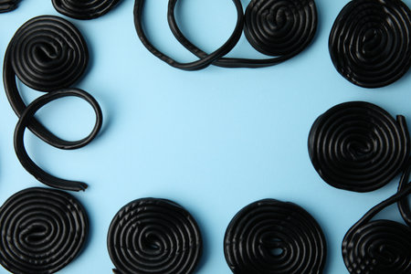 Tasty liquorice candies on light blue background, flat lay. Space for textの写真素材