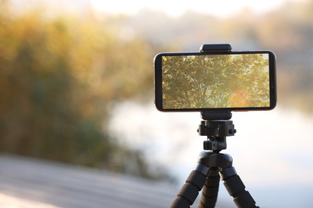 Tripod with smartphone near river. Space for textの写真素材