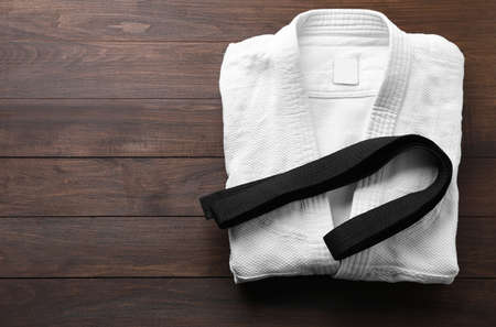 Martial arts uniform and black belt on wooden background, top view. Space for textの写真素材