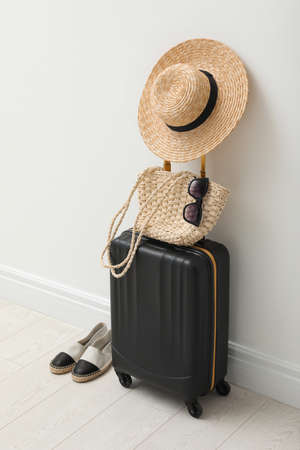Suitcase packed for trip, shoes and summer accessories near white wall indoorsの写真素材