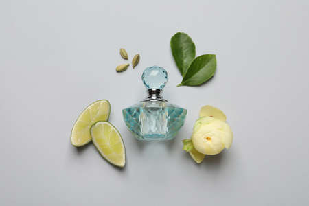 Flat lay composition with bottle of perfume, lime and flower on light gray background