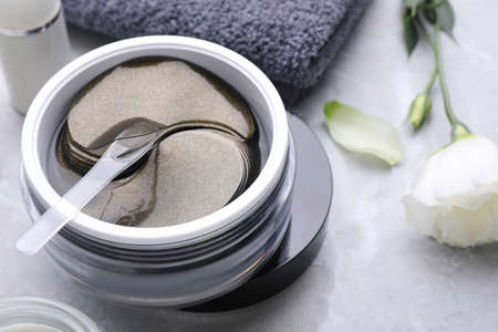 Package of under eye patches and flower on white marble table, closeup. Cosmetic productの写真素材