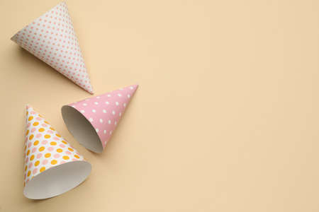 Bright party hats on beige background, flat lay. Space for textの写真素材
