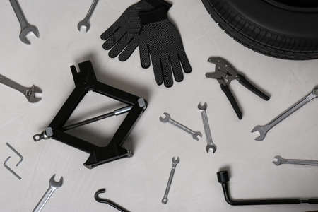 Car wheel, scissor jack, gloves and different tools on gray surface, flat layの写真素材