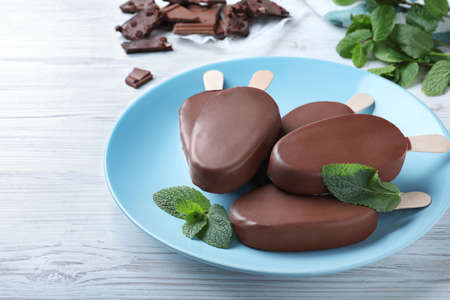Plate with glazed ice cream bars and fresh mint on white wooden tableの写真素材