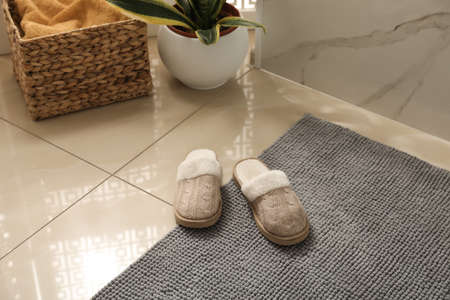 Soft gray bath mat and slippers on floor indoorsの写真素材