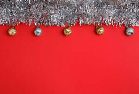 Silver tinsel and Christmas balls on red background, flat lay. Space for textの写真素材