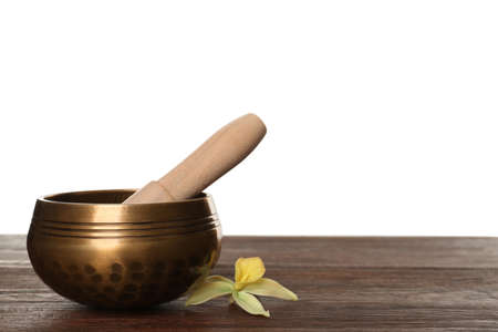 Golden singing bowl, mallet and flower on wooden table against white background, space for textの写真素材