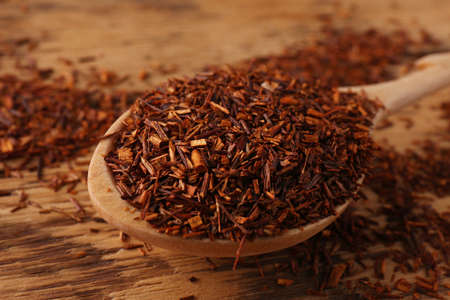 Spoon with dry rooibos leaves on wooden table, closeupの写真素材