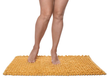 Woman standing on soft orange bath mat against white background, closeupの写真素材