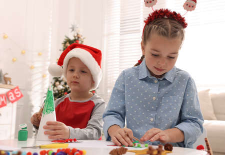 Cute little children making Christmas crafts at table in decorated roomの写真素材