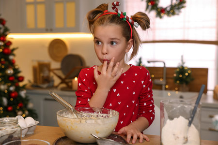Cute little girl having fun while making dough for Christmas cookies in kitchenの写真素材