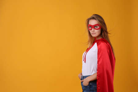 Confident woman wearing superhero cape and mask on yellow background. Space for textの写真素材