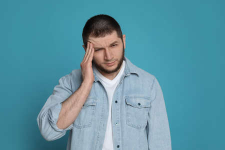 Man suffering from headache on light blue backgroundの写真素材