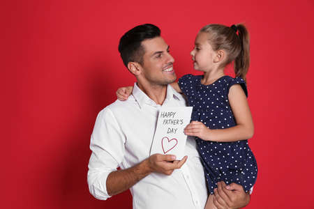 Little girl greeting her dad with Father's Day on red backgroundの写真素材