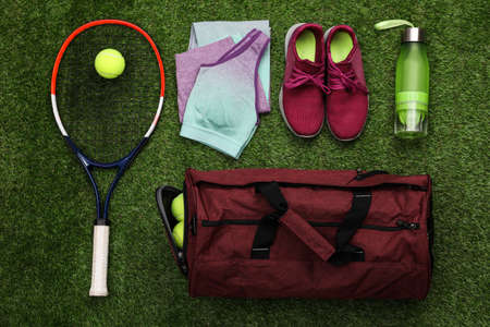 Gym bag and sports equipment on green grass, flat layの写真素材