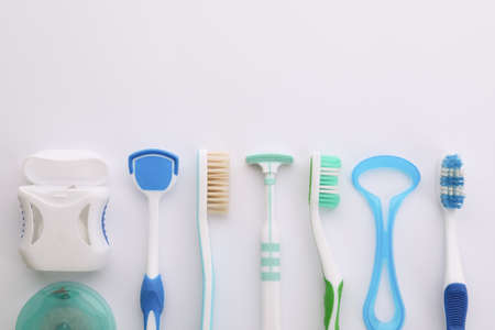 Different tongue cleaners, dental flosses and toothbrushes on white background, top viewの写真素材