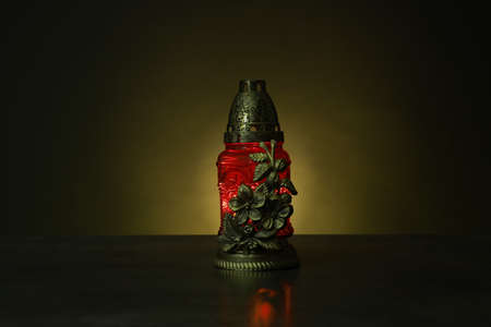 Beautiful glowing red grave light on table in darkness. Symbol of remembrance