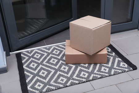 Cardboard boxes on stylish door mat near entranceの写真素材
