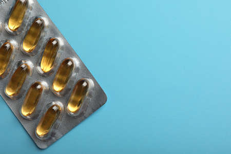 Dietary supplement capsules in blister pack on light blue background, top view. Space for textの写真素材