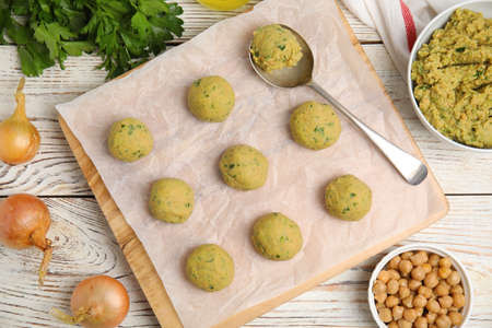 Raw falafel balls and ingredients on white wooden table, flat layの写真素材