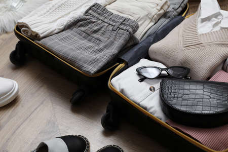 Open suitcase with folded clothes and accessories on floor, closeupの写真素材