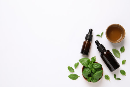 Essential basil oil with fresh leaves on white background, flat lay. Space for textの写真素材