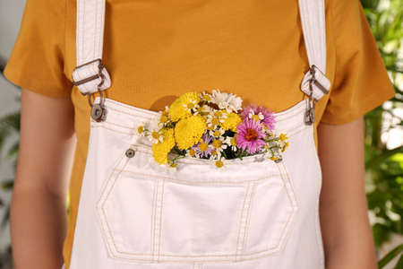 Woman with beautiful tender flowers in white jumpsuit's pocket outdoors, closeupの写真素材