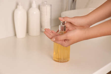 Woman using liquid soap in bathroom, closeup