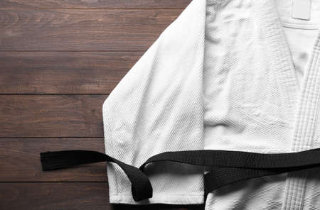 Martial arts uniform with black belt on white wooden background, top view. Space for textの写真素材