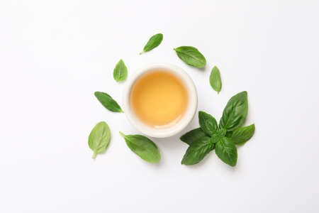 Essential basil oil and fresh leaves on white background, flat layの写真素材