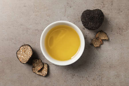 Fresh truffles and oil in bowl on light gray table, flat layの写真素材
