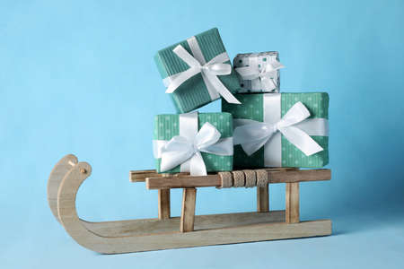 Wooden sleigh with Christmas gift boxes on light blue backgroundの写真素材