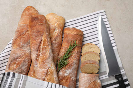 Fresh crispy baguettes and knife on gray table, top view