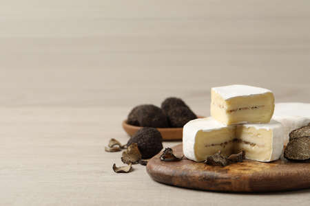 Delicious cheese and fresh black truffles on white wooden table. Space for textの写真素材