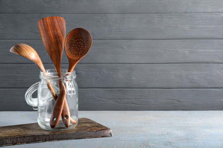 Set of kitchen utensils in holder on gray wooden table, space for textの写真素材